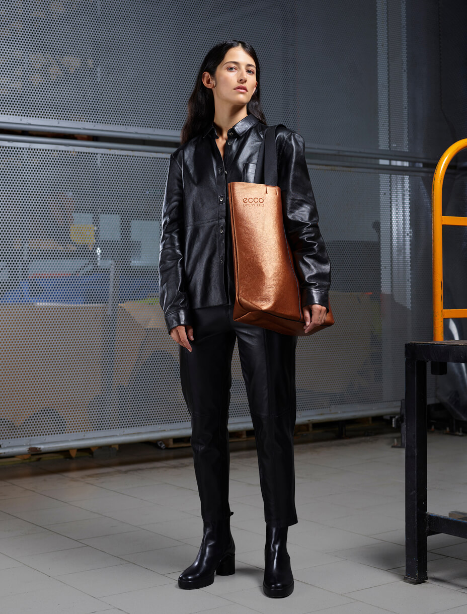 Девушка стоит с коричневой сумкой